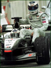 A hapless Hakkinen sits in his car and watches Schumacher go by