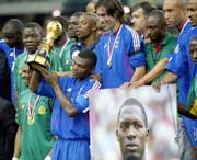 France team captain Marcel Desailly (C) holds the Confederations Cup trophy with players from France and Cameroon near the portrait of late Cameroon player Marc-Vivien Foe