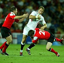 Welshmen Ceri Sweeney and Iestyn Harris tackle Mike Catt of England