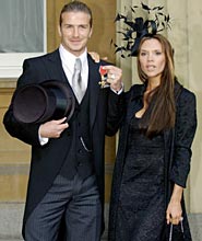 David Beckham with his wife Victoria as he holds the OBE medal.