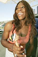 Serena Williams laughs as she is given a bobble head doll replica of herself