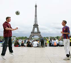 An Arsenal fan and a Barcelona fan have a friendly kickabout in front of the Eiffel Tower in Paris