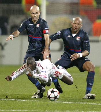 Debrecen's Adamo Coulibaly takes a tumble after being challenged by Olympique Lyon's Cris (left) and Jean-Alain Boumsong