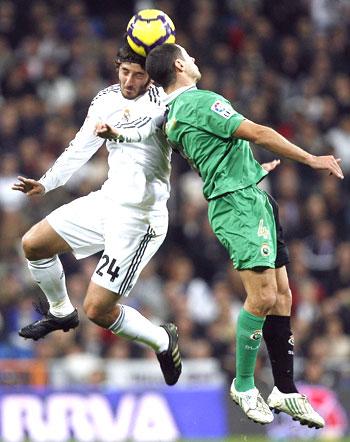 Real Madrid's Granero (left) and Racing Santander's Lacen are involved in an aerial duel during their La Liga match on Saturday