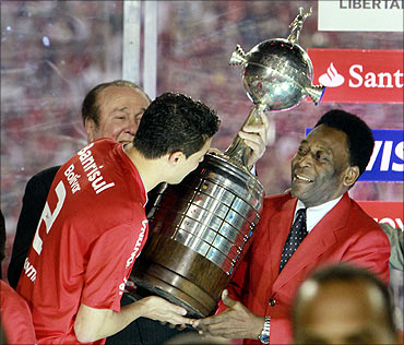 Bolivar, captain of Brazil's Internacional receives the trophy from football legend Pele