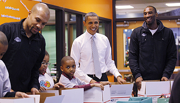 US President Barack Obama (centre) and LA Lakers' Kobe Byrant (right) help put together care packages for members of the military and homeless people at the Boys and Girls Club of Washington on Monday