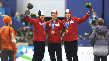 Canada's team pursuit speed skater's Mathieu Giroux, Lucas Makowsky and Denny Morrison stand on the podium as silver medallist Brian Hansen of the US (right) and bronze medallist Mark Tuitert of the Netherlands (left) watch on during the medals ceremony
