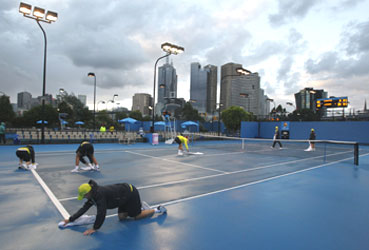 Grounds personnel dry an outer court following a downpour on Monday