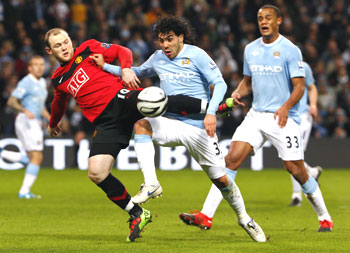 Manchester United's Wayne Rooney (left) challenges Manchester City's Carlos Tevez (centre) during their English League Cup match on Wednesday