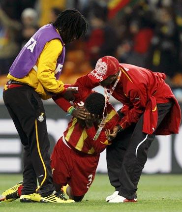 Ghana's Asamoah Gyan (centre) is consoled after the quarter-final match against Uruguay