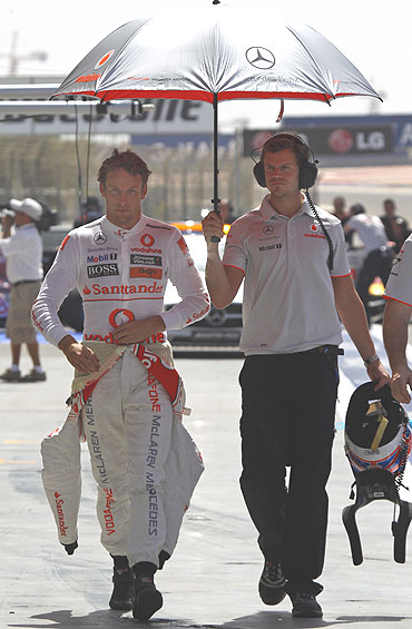 Jenson Button (left) walks in the pits