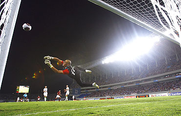 Algeria's goalkeeper Faouzi Chaouchi dives as Egypt's Emad Moteab takes a penalty shot during their African Nations Cup semi-final