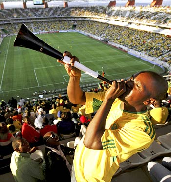 A fan blows the vuvuzela trumpet