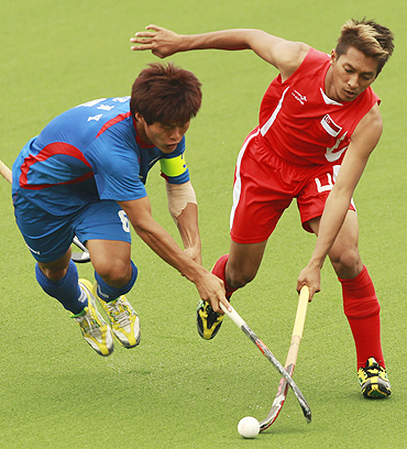 Mohamed Ishak Ismail of Singapore (right) challenges Lee Nam-yong of South Korea during their hockey match on Sunday