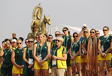 Australian team members stand for the national anthem during the team's flag-raising ceremony at the Commonwealth Games Village in Delhi