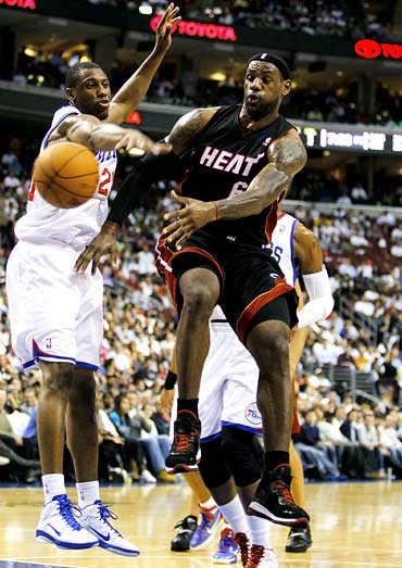 Miami Heat forward LeBron James (right) tries to evade a challenge from Thaddeus Young of Philadelphia 76ers