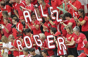 Fans of Roger Federer hold up a placard which reads: 'GO ROGER'