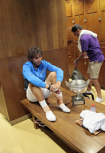 Rafael Nadal rests with his French Open trophy in the players dressing room