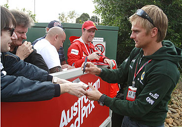 Lotus Formula One driver Heikki Kovalainen of Finland signs autographs