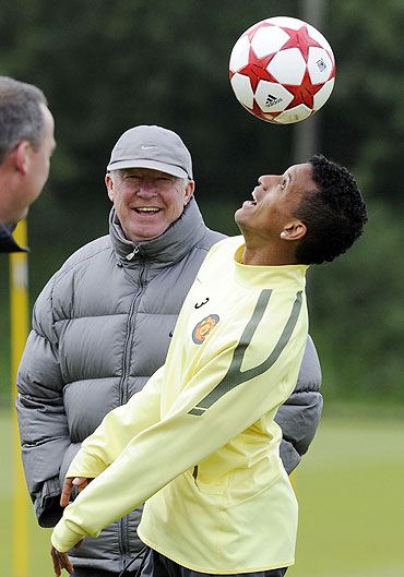 Manchester United's Nani (right) heads the ball as coach Alex Ferguson looks on