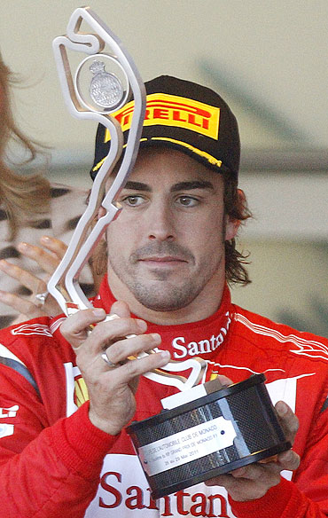 Ferrari's driver Fernando Alonso holds his trophy after finishing second