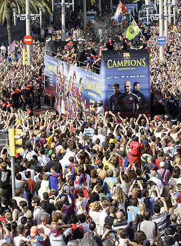 Barcelona's players celebrate atop a bus with their supporters on the streets of Barcelona on Sunday
