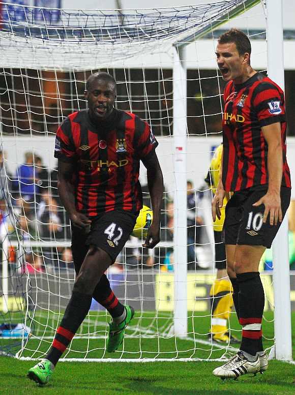 Manchester City's Yaya Toure (L) celebrates with teammate Edin Dzeko during their match between Queens Park Rangers