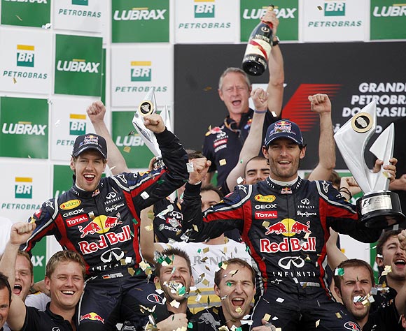 Red Bull's Sebastian Vettel (left) and teammate Mark Webber celebrate with their team members after the Brazilian GP on Sunday
