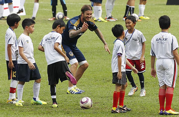 Los Angeles Galaxy's David Beckham (centre) interacts with kids during a coaching clinic at Bung Karno stadium in Jakarta