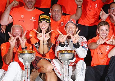 Jenson Button celebrates in the pitlane with his girlfriend Jessica Michibata and teammates