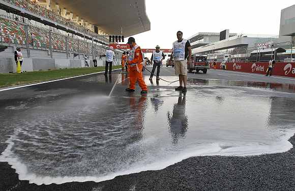 Workers spray foam to clean the dirt off the track at the Buddh International Circuit in Greater Noida