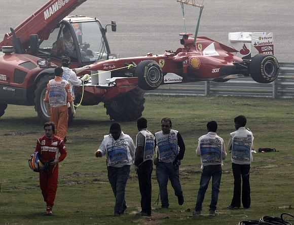 Ferrari Formula One driver Fernando Alonso walks inside the barrier after he retired from the first practice session