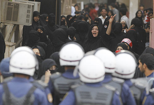 Protesters run for cover after riot police storm in to disperse them during an anti-government rally in Manama
