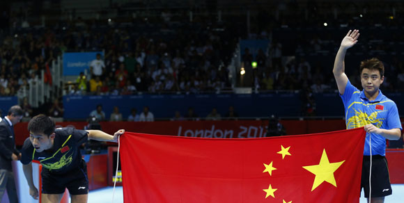 China's Zhang Jike bows as compatriot Wang Hao waves as they celebrate with a Chinese flag after their men's singles gold medal table tennis match