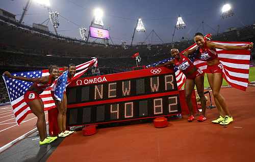 Members of the U.S. team pose with their national flags after winning the women's 4x100m relay final during the London 2012 Olympic Games