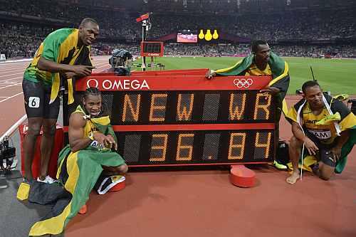 Usain Bolt, Yohan Blake, Michael Frater and Nesta Carter of Jamaica celebrate next to the clock after winning gold and setting a new world record of 36.84 during the Men's 4 x 100m Relay Final