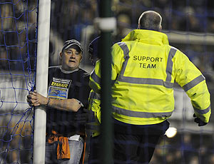 A man (left) handcuffs himself to the goalpost during the English Premier League soccer match between Everton and Manchester City