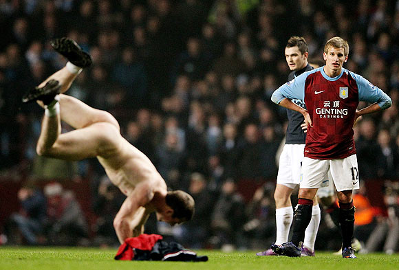 Marc Albrighton of Aston Villa and Adam Johnson of Manchester City look on as a streaker runs on to the pitch during their match on Sunday