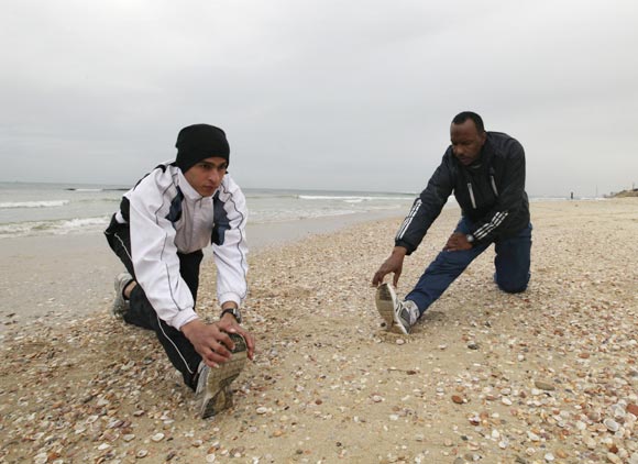 Gaza runner Bahaa al-Farra (left) and his coach Majed Abu Maraheel stretch during a training session