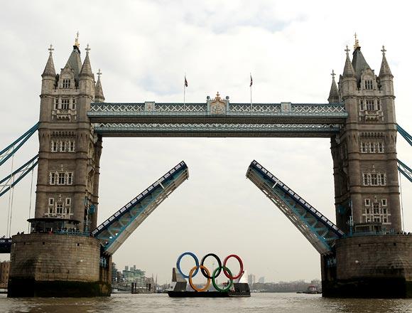 The giant Olympic rings are towed on The River Thames past The Tower of London