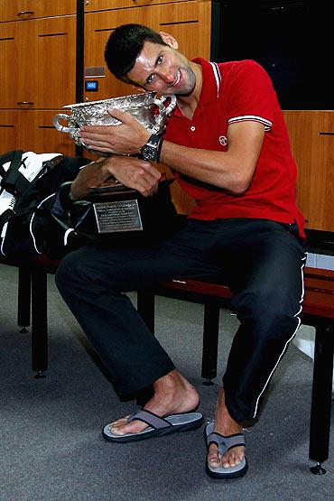 Novak Djokovic of Serbia poses with the Norman Brookes Challenge Cup in the players locker room