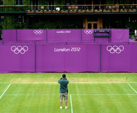 A workman takes a photograph on Court 10 as Olympic hoarding is erected at the All England Lawn Tennis Club (AELTC) as preparations are made for the London 2012 Olympic Games