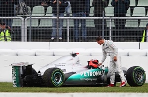 Michael Schumacher of Germany and Mercedes GP stands with his car after he spun and 