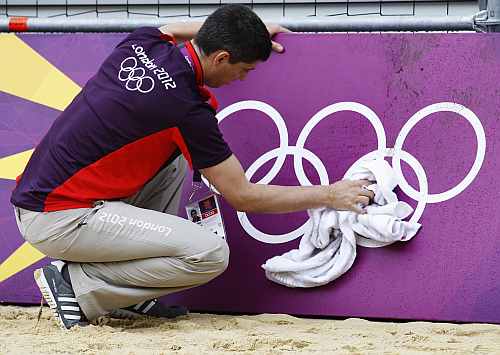 Simon Drew wipes down hoarding surrounding a practice beach volley ball court