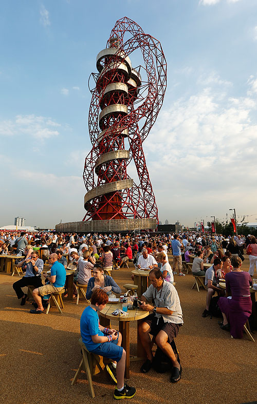 Patrons relax in front of the ArcelorMittal Orbit tower at the Olympic Park in London