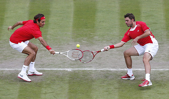 Switzerland's Roger Federer (left) and Stanislas Wawrinka play a return agianst Japan's Go Soeda and Kei Nishikori in their men's doubles match during the London Olympics on Monday