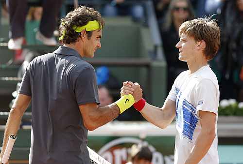 Roger Federer of Switzerland (L) shakes hands with David Goffin of Belgium after winning his match during the French Open