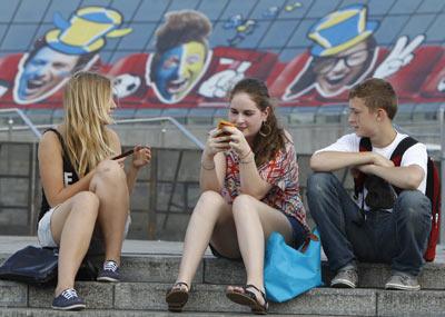 Teenagers sit in front of EURO-2012-themed decoration in Kiev