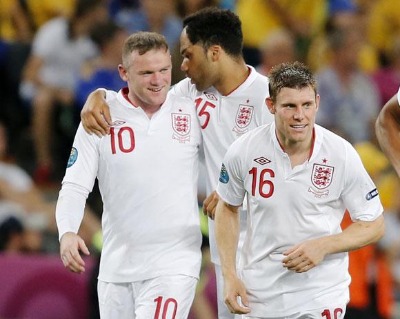 England's Wayne Rooney (L) celebrates his goal against Ukraine with team mates Joleon Lescott and James Milner (R) during their Group D match at the Donbass Arena in Donetsk