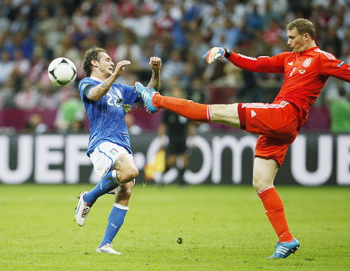Germany's goalkeeper Manuel Neuer (right) kicks the ball in front of Italy's Alessandro Diamanti